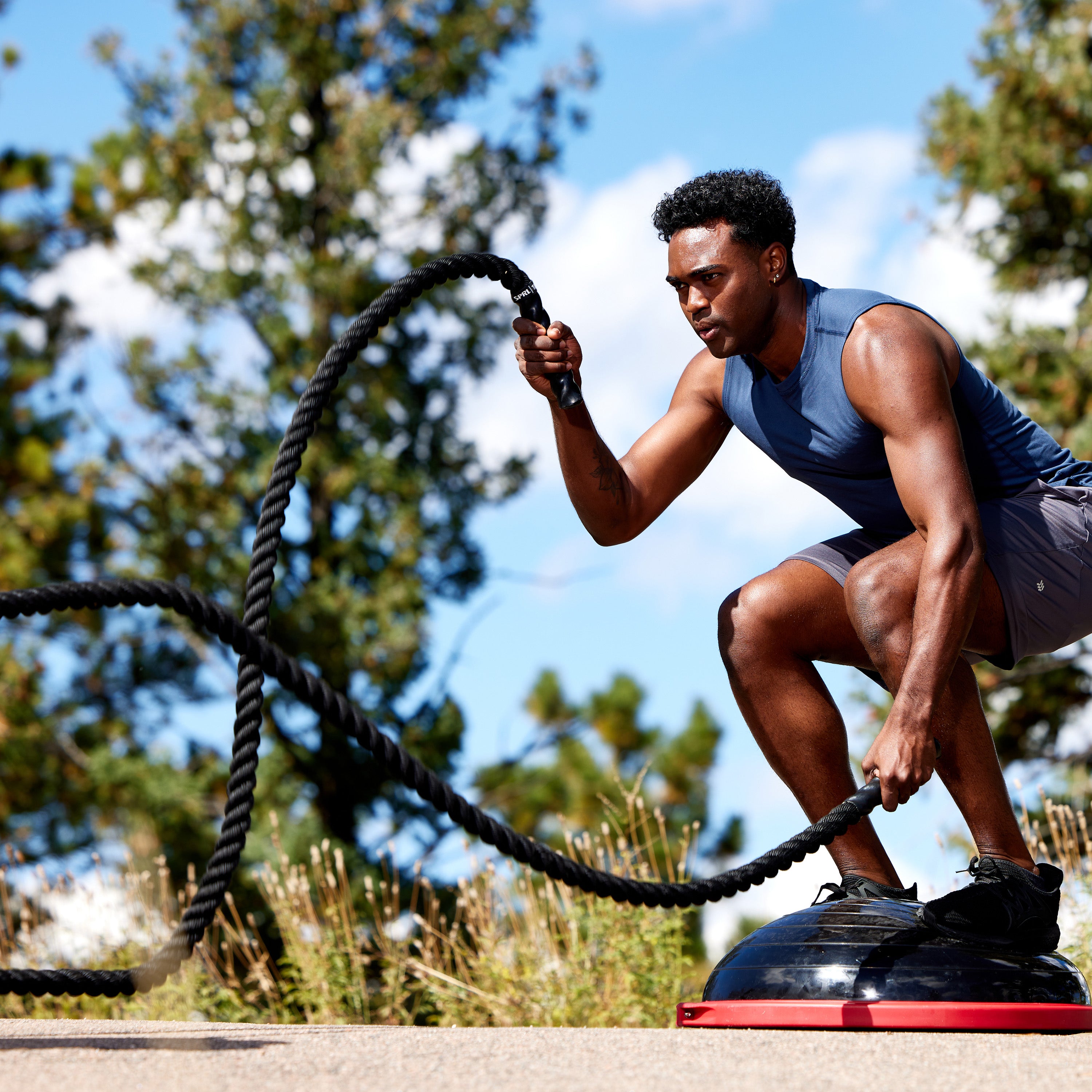 Person standing on the SPRI Balance Trainer while using the Conditioning Rope 